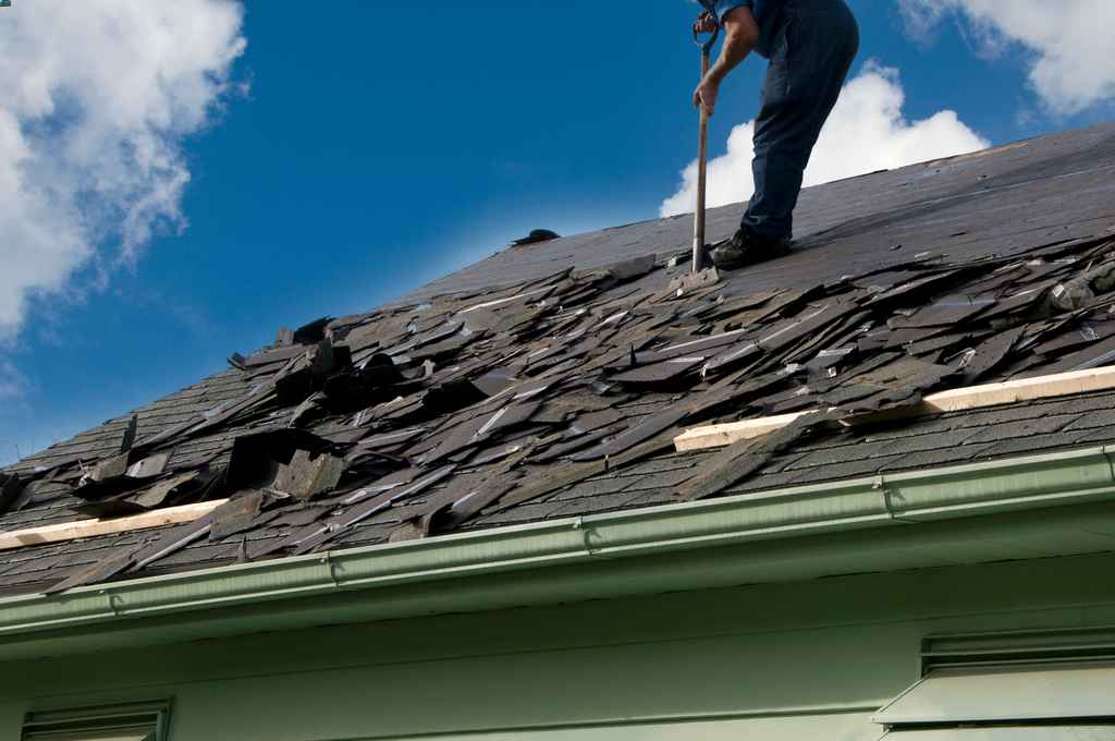 Roofer removing asphalt shingle roofing during a Roof replacement