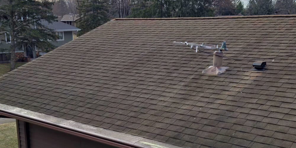 Aging asphalt shingle roof with moss during a roof inspection