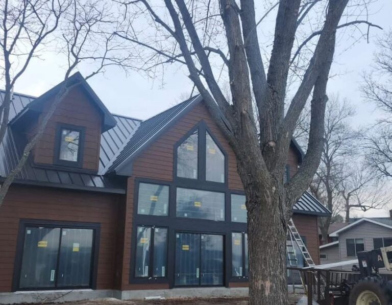 Black standing seam metal roof on a new-construction Minnesota home with a large gable window wall